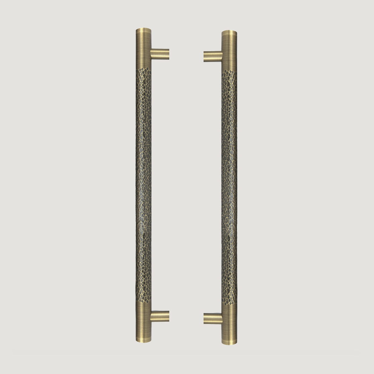 Two Martello solid brass front door pull handles with hammered grips and smooth ends on a warm grey background; sold individually.