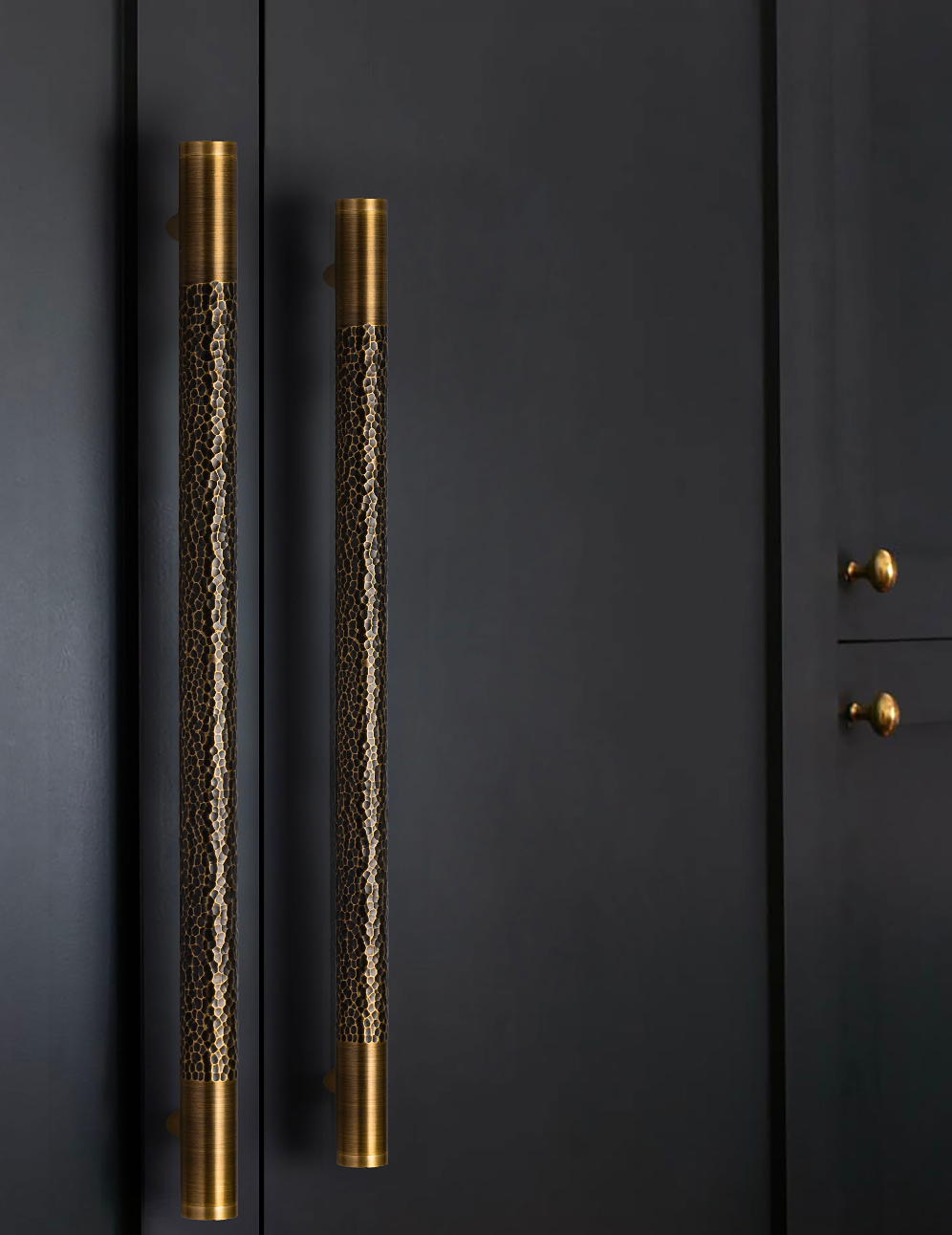 Martello solid brass hammered pull handles mounted vertically on dark panelled doors.