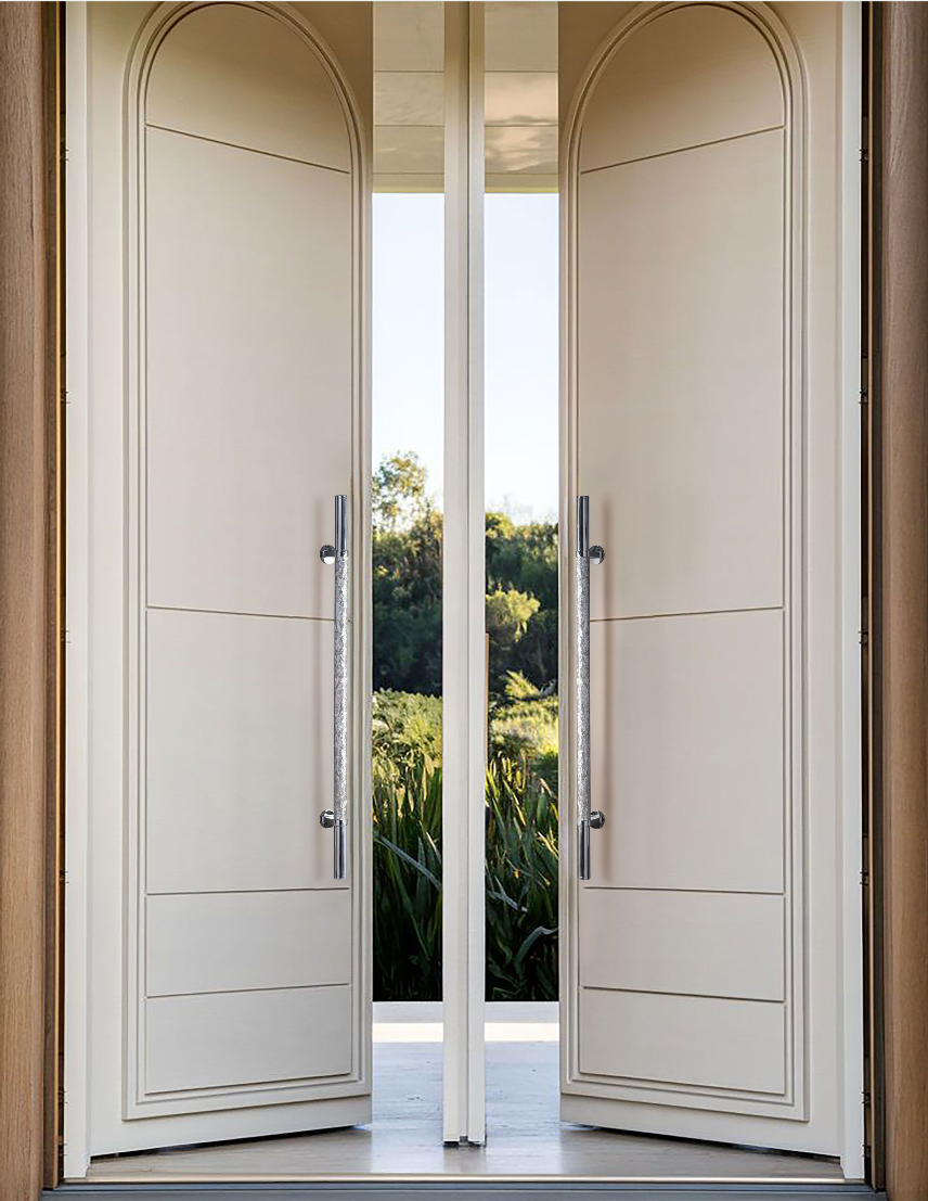Two reflective textured pull handles mounted on tall white double doors in an entryway.