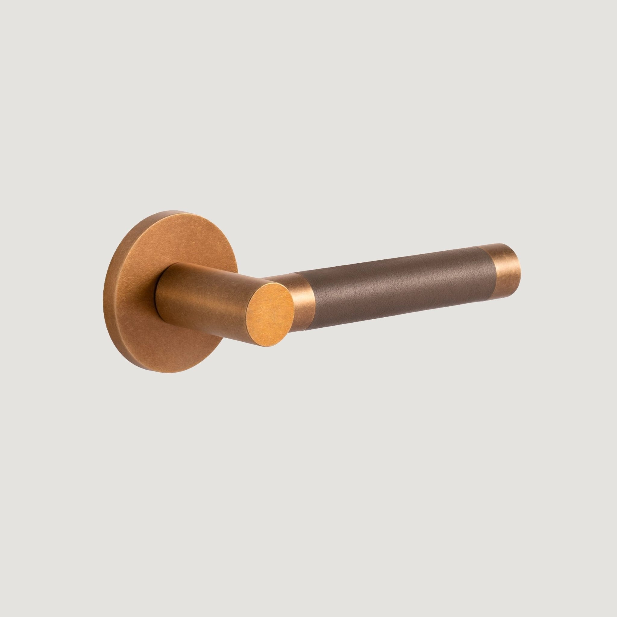 Cavallo Piatto solid brass door lever with warm Aged Brass frame and hand-stitched grey leather grip — Bergamo Design